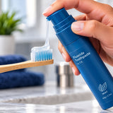 Blue toothpaste being pumped onto a bamboo toothbrush