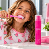 Girl brushing her teeth beside a pink toothpaste dispenser